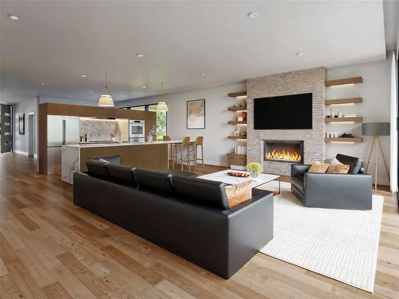 Spacious open-concept living area featuring wood-finish flooring, a stone-clad fireplace, and built-in shelving