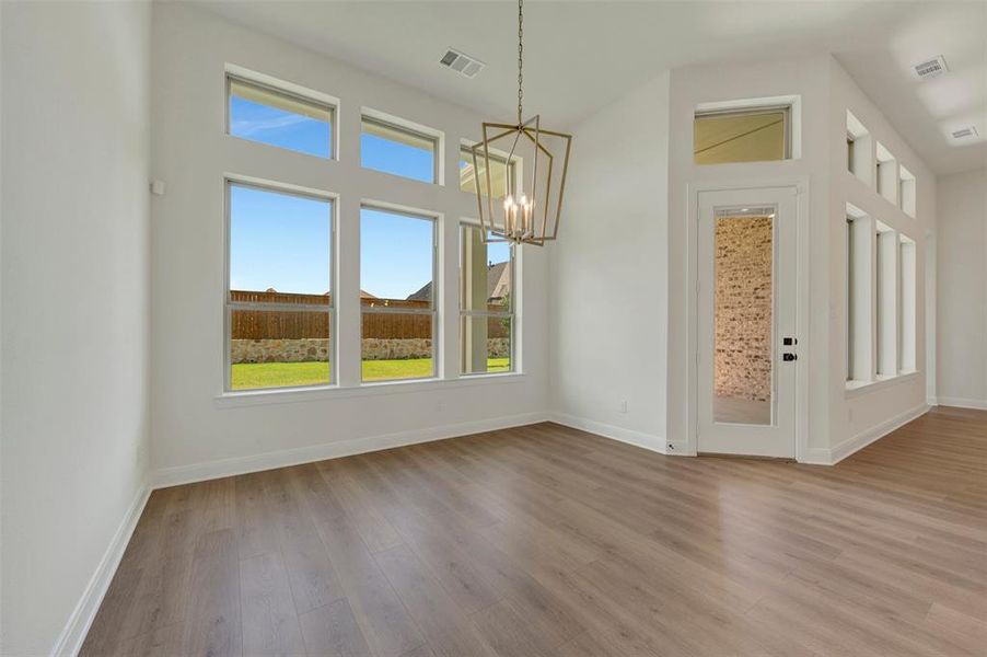Vaulted ceiling with an architectural light fixture, wood-finish flooring, white baseboards, and expansive windows Vaulted ceiling with an architectural light fixture, wood-finish flooring, white baseboards, and expansive windows