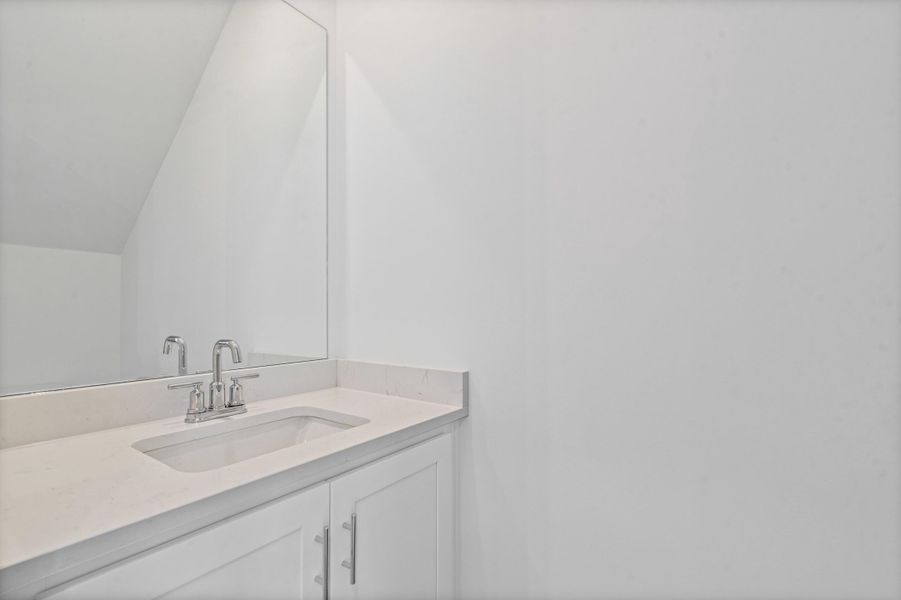 White vanity with integrated sink, chrome faucet, and expansive wall-mounted mirror White vanity with integrated sink, chrome faucet, and expansive wall-mounted mirror