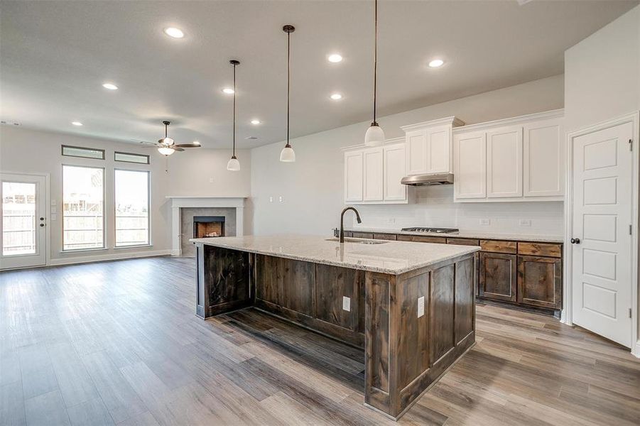 Kitchen featuring white cabinetry, ceiling fan, a kitchen island with sink, and sink