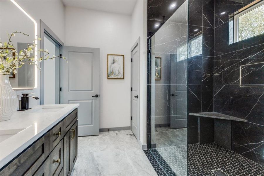 Bathroom featuring tiled shower and vanity