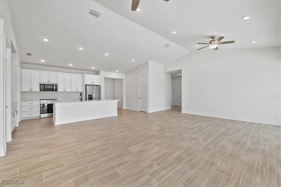 Unfurnished living room with recessed lighting, lofted ceiling, ceiling fan, and wood finish floors