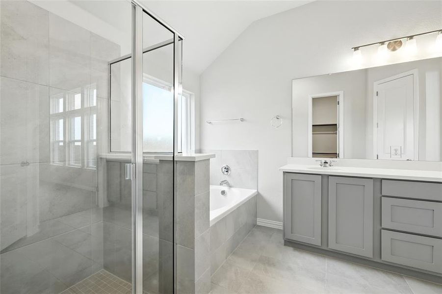 Bathroom with vaulted ceiling, vanity, a garden tub, a stall shower, and light tile patterned floors