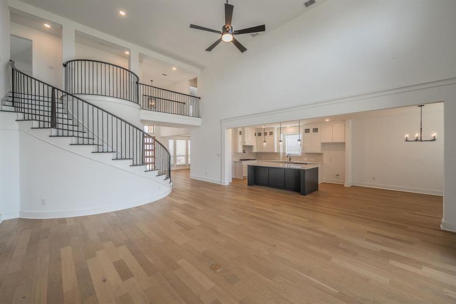 Grand entrance featuring a curved staircase with black metal railings, light wood flooring, and a high ceiling