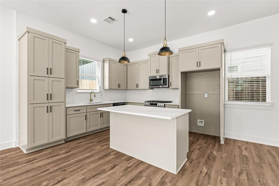 Sophisticated and fully equipped. High-end built-in appliances, a classic subway tile backsplash, and dramatic matte-black and gold pendant lights elevate your daily cooking experience.