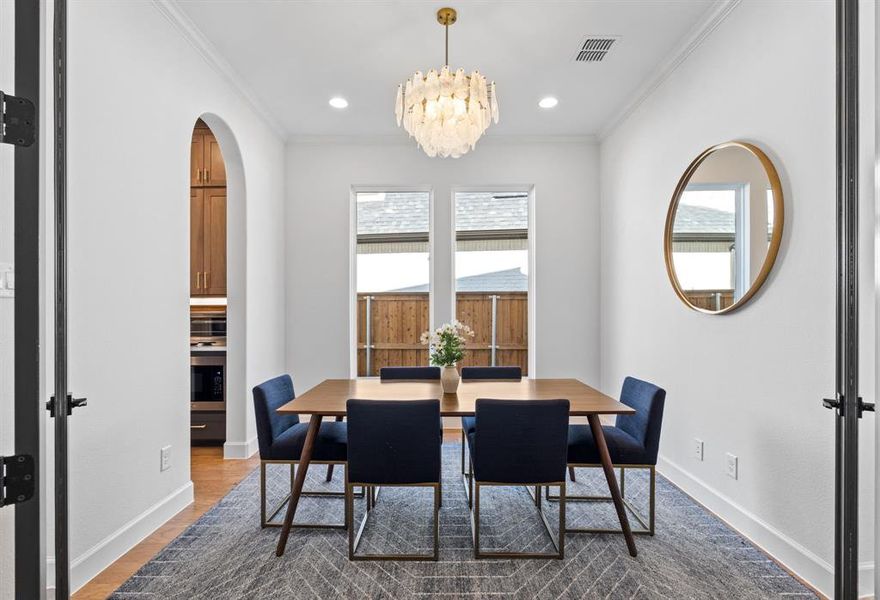 Dining space featuring crown molding, light wood-style floors, arched walkways, recessed lighting, and a chandelier Dining space featuring crown molding, light wood-style floors, arched walkways, recessed lighting, and a chandelier