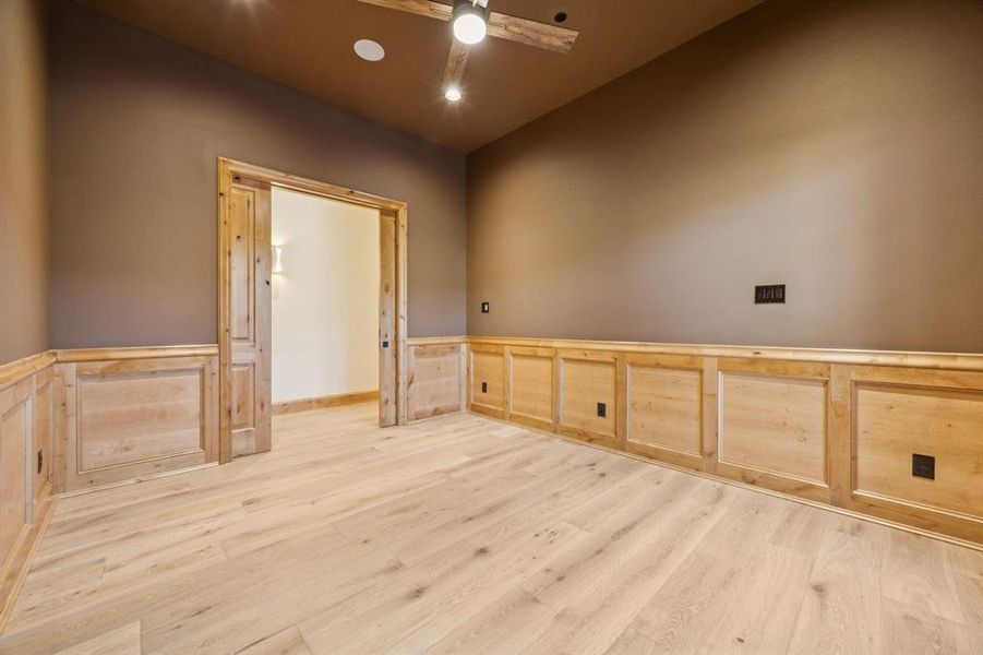 Spare room with a wainscoted wall, a decorative wall, light wood-style floors, and ceiling fan