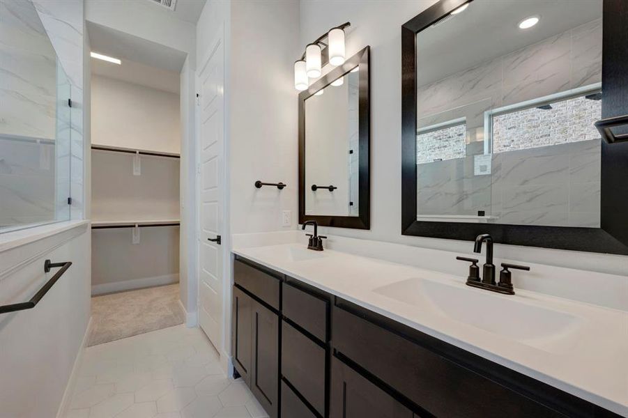 Full bathroom with a spacious closet, double vanity, and a marble finish shower