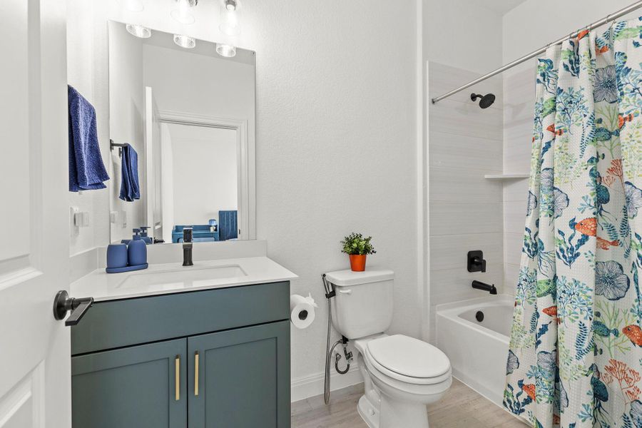 Bathroom featuring vanity, shower / tub combo, and light wood-style flooring