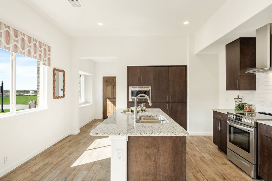 Kitchen with granite island, dark wood cabinets, stainless steel appliances, and hardwood floors
