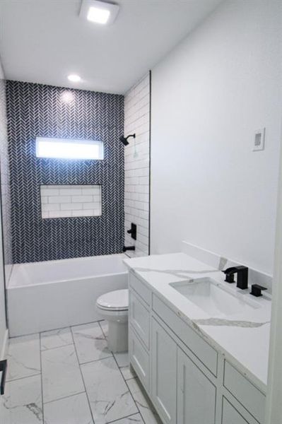 Full bath featuring vanity, shower / tub combination, and light marble finish flooring Full bath featuring vanity, shower / tub combination, and light marble finish flooring