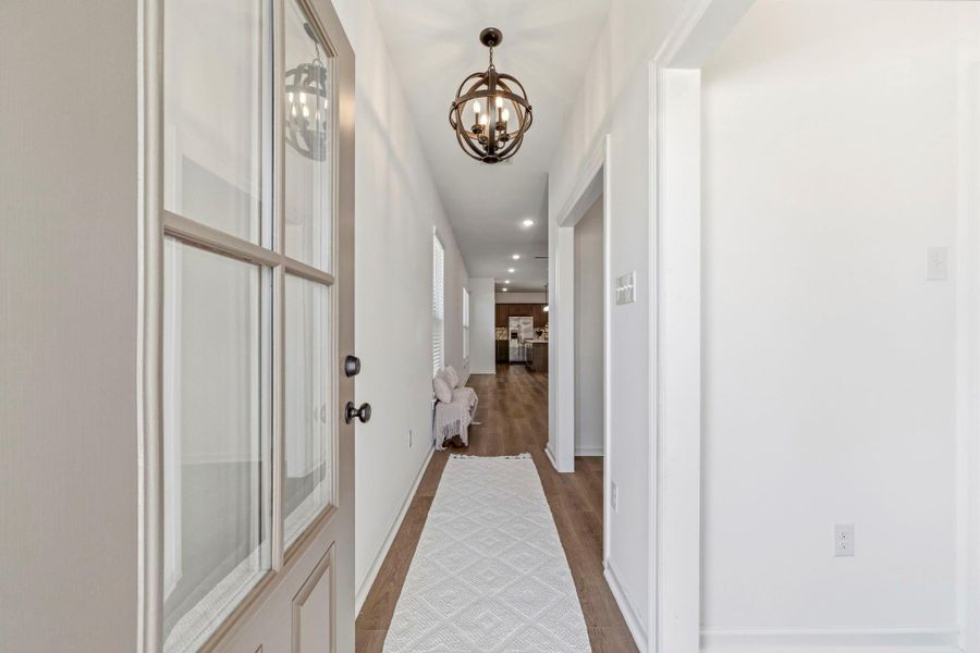 Step inside to a welcoming foyer featuring luxury vinyl plank flooring, soaring ceilings, elegant designer lighting, and a versatile flex space just off the entry—perfect for a home office, formal dining room, or playroom.