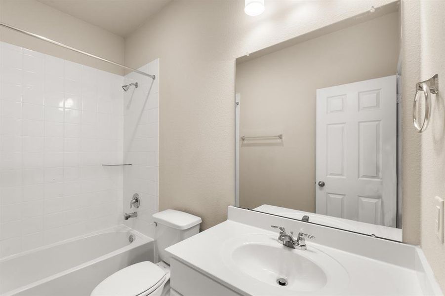 The secondary bath features tile flooring, white cabinetry and light countertops and a shower/tub combo. Perfect for accommodating any visiting family and friends.