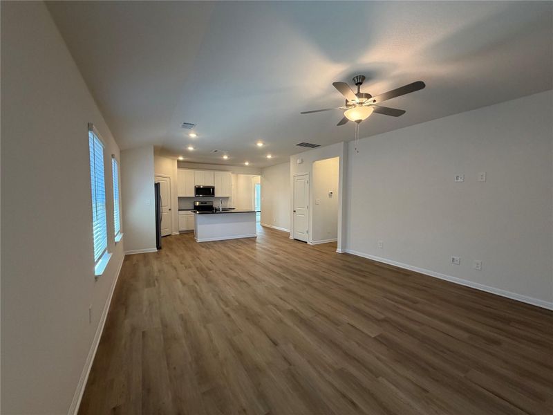 Unfurnished living room featuring dark wood-style floors, ceiling fan, and recessed lighting