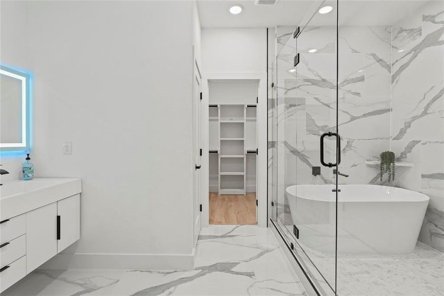 Bathroom with light marble finish flooring, vanity, a freestanding bath, a spacious closet, and a marble finish shower Bathroom with light marble finish flooring, vanity, a freestanding bath, a spacious closet, and a marble finish shower