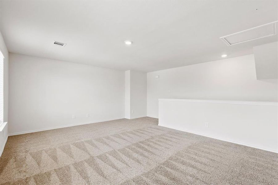 Spacious room featuring neutral carpet flooring, recessed lighting, white walls, and a half-wall partition