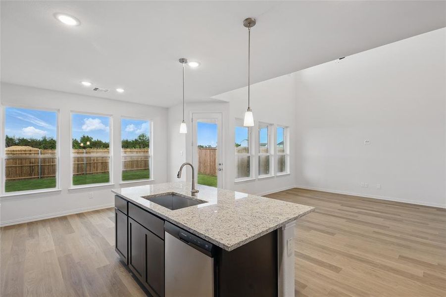 Kitchen featuring dishwasher, a sink, light wood-style flooring, pendant lighting, and a kitchen island with sink Kitchen featuring dishwasher, a sink, light wood-style flooring, pendant lighting, and a kitchen island with sink