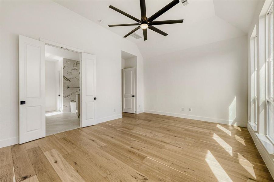 Unfurnished bedroom with lofted ceiling, light wood-style floors, and ceiling fan