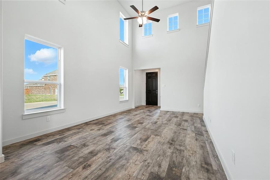 Spare room featuring a towering ceiling, wood finished floors, and ceiling fan Spare room featuring a towering ceiling, wood finished floors, and ceiling fan