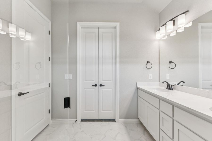 Full bathroom featuring double vanity, light marble finish floors, and a closet Full bathroom featuring double vanity, light marble finish floors, and a closet