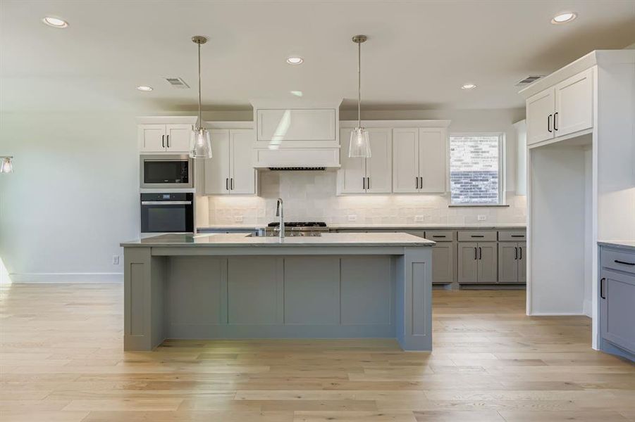 Kitchen featuring recessed lighting, backsplash, decorative light fixtures, appliances with stainless steel finishes, and a center island with sink Kitchen featuring recessed lighting, backsplash, decorative light fixtures, appliances with stainless steel finishes, and a center island with sink