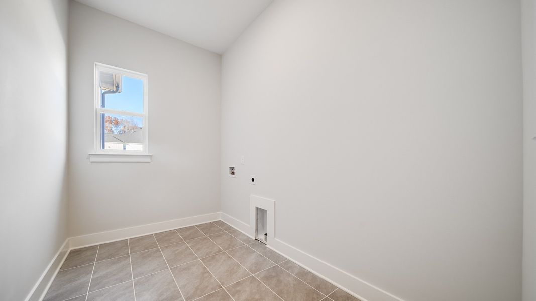 Dedicated laundry room with hookups, tile floor, and window