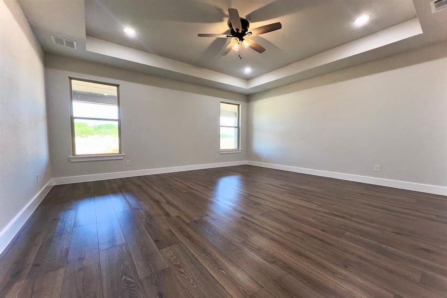 Unfurnished room with a raised ceiling, dark  finished floors, ceiling fan, and recessed lighting