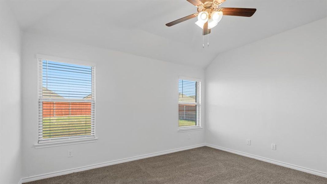 Spare room with lofted ceiling, dark colored carpet, and a ceiling fan