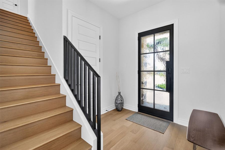 A graceful staircase with wood treads and a modern black railing welcomes you into a bright, open entry. A graceful staircase with wood treads and a modern black railing welcomes you into a bright, open entry.