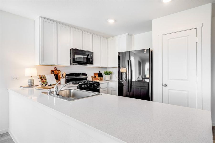 Kitchen with kitchen peninsula, white cabinetry, sink, and black appliances