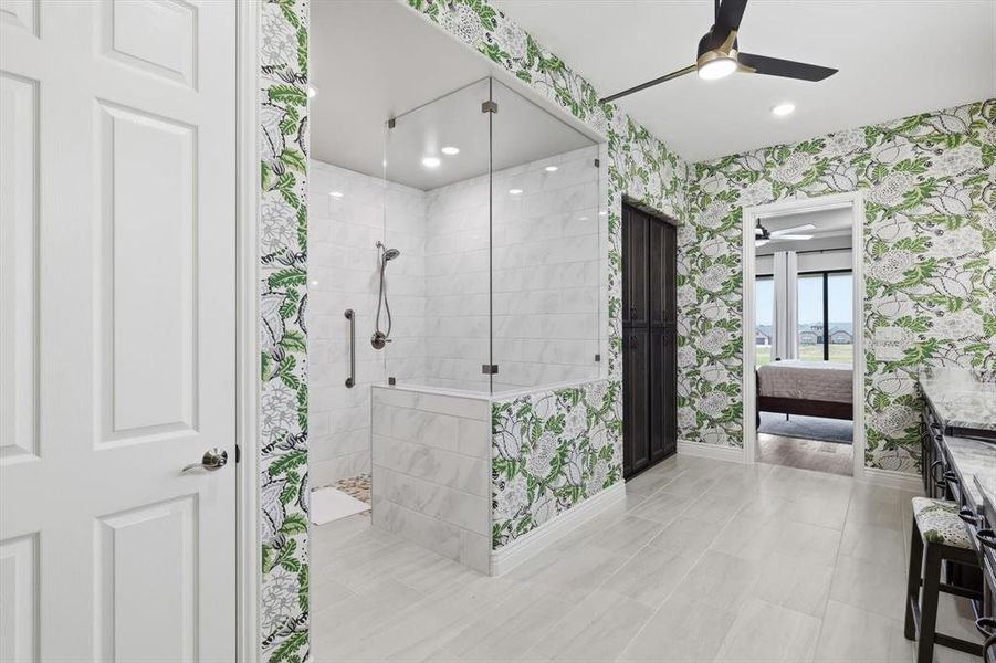 Spa-Inspired Primary En-Suite Bath with Coordinating Designer Thibaut Wallpaper, Coordinating Portinari Dolomite Countertops, Spacious Curb-less Shower, Private Water Closet, and an Oversized Walk-in Closet.