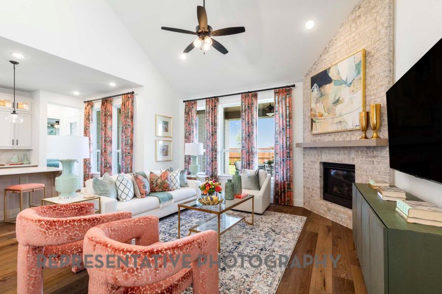 Living area with dark wood-style flooring, high vaulted ceiling, a brick fireplace, ceiling fan, and recessed lighting Living area with dark wood-style flooring, high vaulted ceiling, a brick fireplace, ceiling fan, and recessed lighting