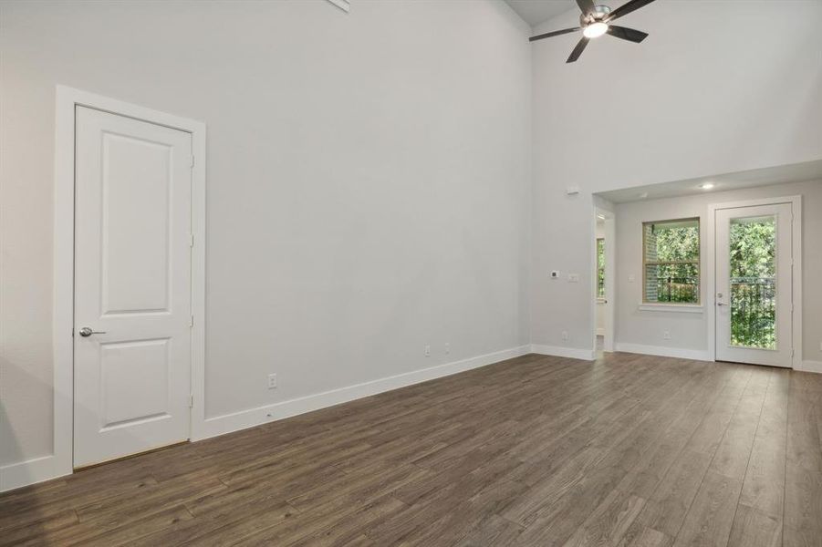 Unfurnished living room with ceiling fan, dark wood finished floors, a towering ceiling, and baseboards