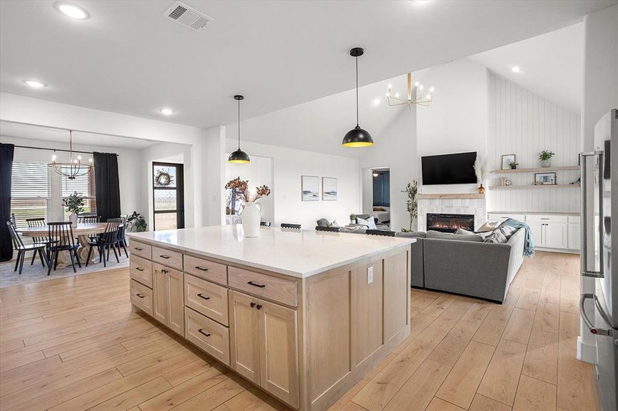 Kitchen with decorative light fixtures, lofted ceiling, a chandelier, and a tiled fireplace