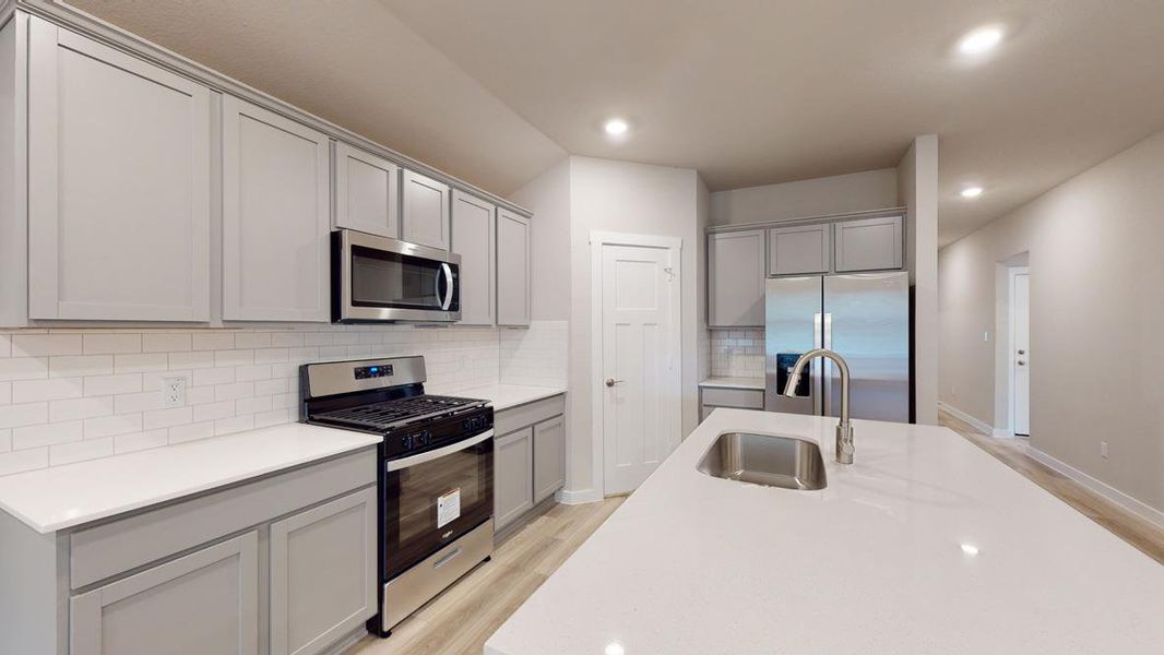 Kitchen featuring stainless steel appliances, tasteful backsplash, light wood-style flooring, gray cabinetry, and recessed lighting
