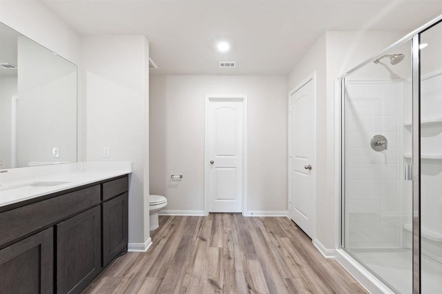 Bathroom featuring hardwood / wood-style floors, a shower with door, toilet, and vanity