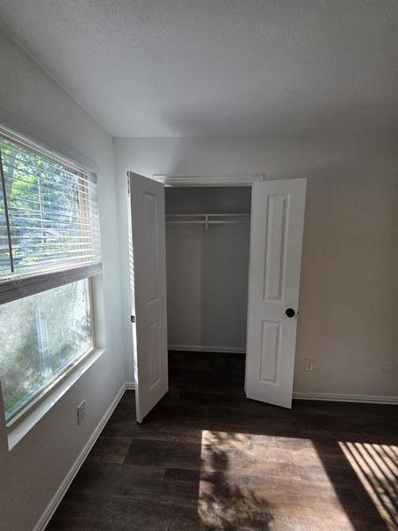Unfurnished bedroom with wood finished floors, a closet, and a textured ceiling Unfurnished bedroom with wood finished floors, a closet, and a textured ceiling