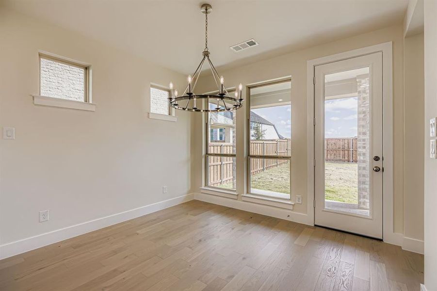 Unfurnished dining area with plenty of natural light, light wood-type flooring, and a chandelier Unfurnished dining area with plenty of natural light, light wood-type flooring, and a chandelier