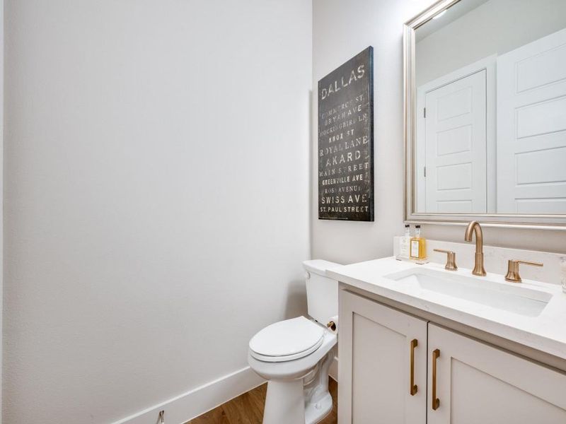 Bathroom featuring wood finished floors, vanity, toilet, and baseboards