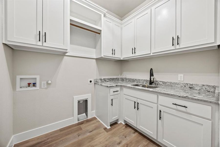 Laundry room with light wood finished floors, hookup for a gas dryer, hookup for a washing machine, hookup for an electric dryer, and cabinet space Laundry room with light wood finished floors, hookup for a gas dryer, hookup for a washing machine, hookup for an electric dryer, and cabinet space