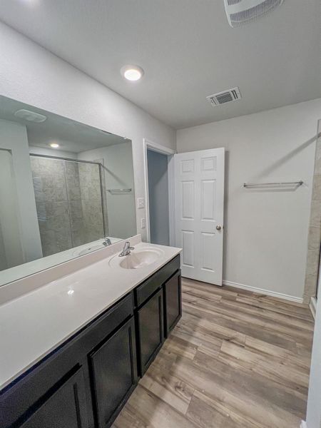 Full bath with a stall shower, light wood finished floors, and vanity