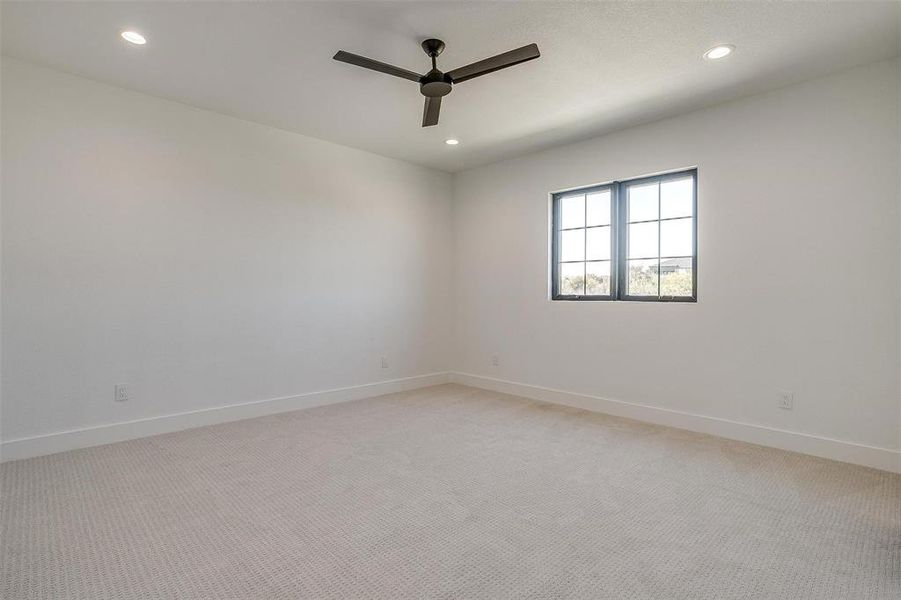 Empty room with light colored carpet and ceiling fan