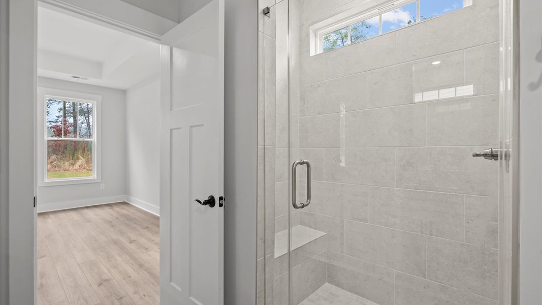 Memorable mornings begin in this elegant primary bathroom with tiled walk-in shower and double vanity