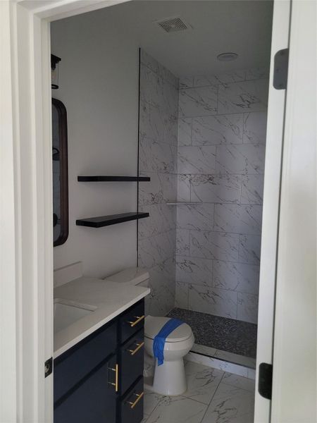 A refined bath with a sleek marble-tiled shower and dark cabinetry offers practical elegance.