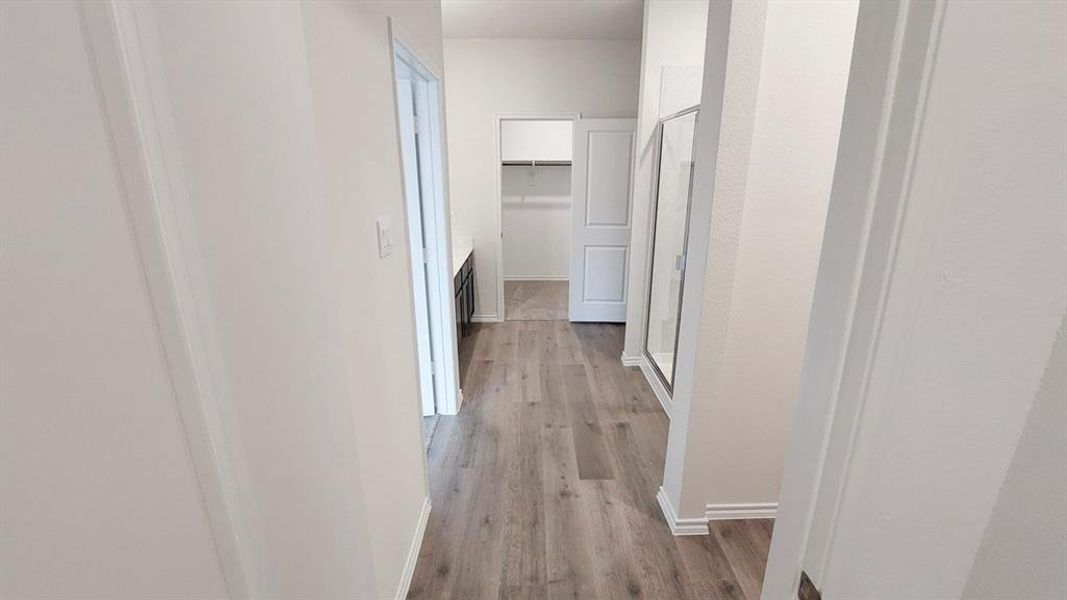 Corridor featuring light wood-style floors and baseboards Corridor featuring light wood-style floors and baseboards
