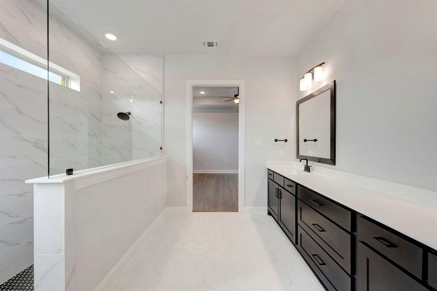 Bathroom featuring a marble finish shower, vanity, and recessed lighting