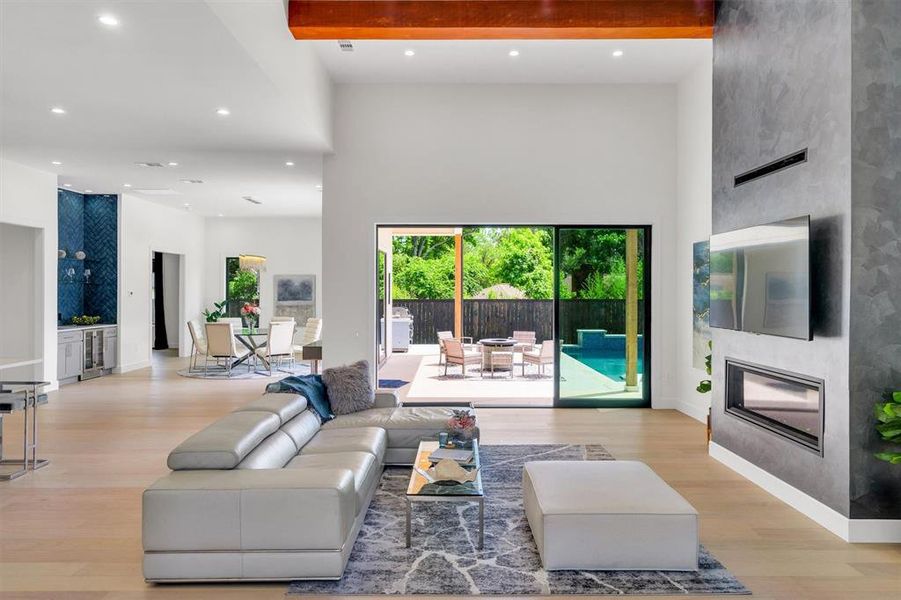Living area with light wood finished floors, recessed lighting, wine cooler, and a high ceiling