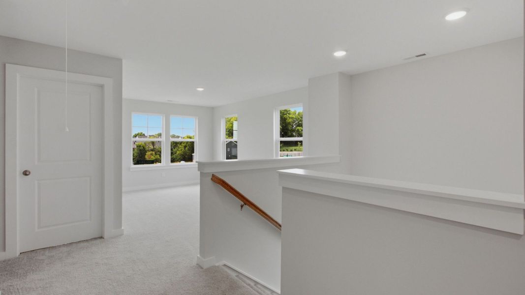 Second floor landing with nearby loft area and door to dedicated laundry room