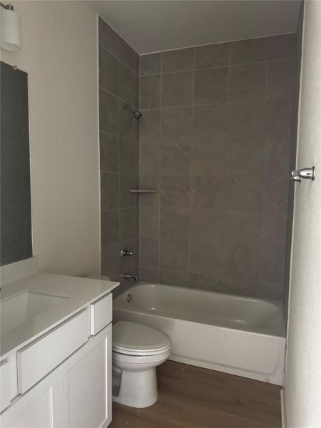 Bathroom featuring vanity, shower combination, and dark wood-style floors Bathroom featuring vanity, shower combination, and dark wood-style floors