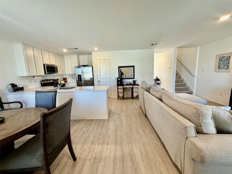 Kitchen featuring white cabinets, appliances with stainless steel finishes, light countertops, a peninsula, and a textured ceiling